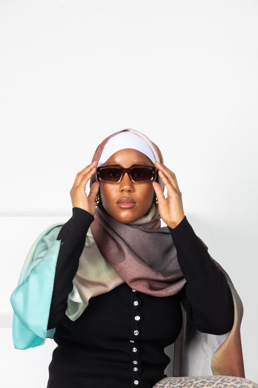 Woman wearing a hijab and sunglasses with a white background