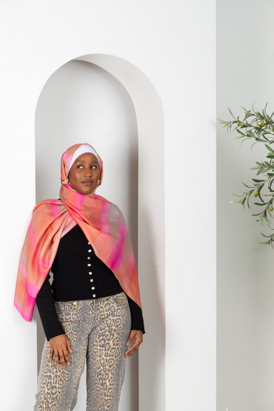 Woman wearing a colorful scarf standing against a white archway.